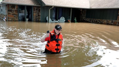 Tulsa County Sheriff's Deputy Miranda Munson makes her way back to a fan boat after checking a flooded house for occupants in the Town and Country neighborhood in Sand Springs, Oklahoma. Tulsa World via AP