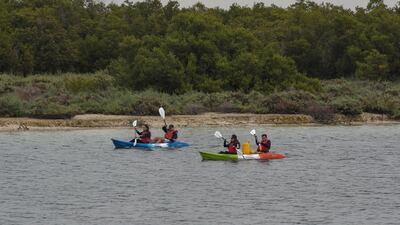 Kayakers paddle through the rain.