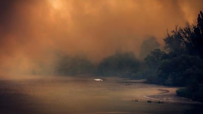 This handout photo released on July 26, 2026 and taken on July 24, 2026 by Spain's Military Emergencies Unit (UME) shows some pedalo boats on a reservoir shrouded in smoke from a wildfire near Navas del Rey, 55 kilometers southwest of Madrid. Spain faces two crucial days to bring raging wildfires under control before weather conditions worsen, authorities said on July 27, 2026, though they were making some progress and planned to start returning evacuees to certain areas. The wildfires that broke out in forested areas around the Spanish capital at the height of the summer holidays have forced some 60,000 people to flee their homes, often with just minutes' notice, leaving pets and medicine behind. AFP