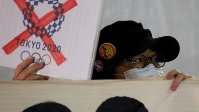 A protester demanding cancellation of the Tokyo 2020 Olympic Games holds a banner in front of the National Stadium, the main stadium of Tokyo 2020 Olympics and Paralympics, while Thomas Bach, President of the IOC visits the site in Tokyo. Reuters