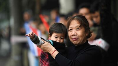 A woman and a child wave as Kim Jong-un's motorcade drives past in Hanoi. AFP