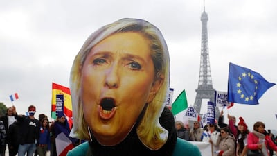 A woman wears a mask depicting the defeated far-right French presidential election candidate Marine Le Pen in front of the Eiffel Tower in Paris on May 8, 2017. Francois Guillot / AFP