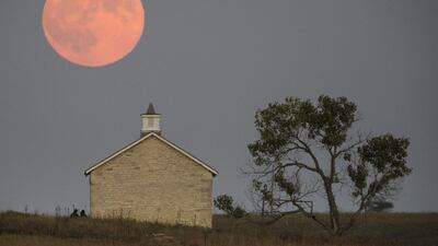 A super moon rises over the Lower Fox Creek School near Strong City, Kan., Sunday, Sept. 27, 2015. It was the first time Sunday since 1982 that a total lunar eclipse was combined with a supermoon. Travis Heying / The Wichita Eagle via AP