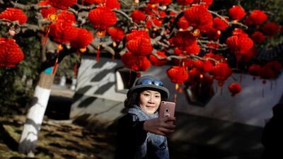 A woman takes a selfie in front of a tree decorated with red lanterns in Ditan Park in Beijing, China. Reuters