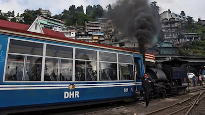 A man climbs down a Darjeeling Himalayan Railway train at a station in Darjeeling.