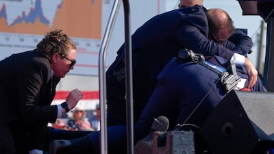 Trump is covered by Secret Service agents on stage. AP