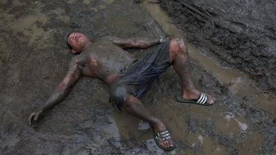 A man lies in the mud after digging a drainage channel to prevent flooding around tents in the aftermath of the June 24 earthquakes in Venezuela. Reuters
