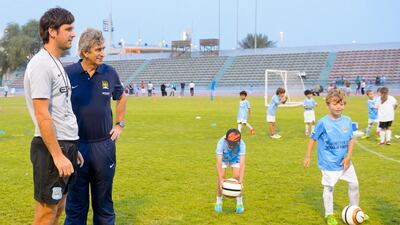 Manchester City Football Club manager Manuel Pellegrini, right, and star midfielder Samir Nasri at a coaching session at the Manchester City Football School in Abu Dhabi. Courtesy City Football Schools