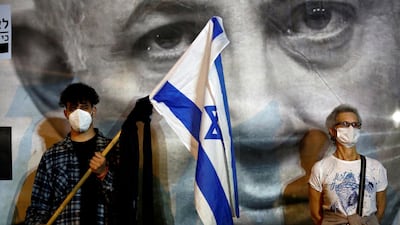 A man wearing a protective face mask holds an Israel's flag as Israelis demonstrate against Israel's Prime Minister Benjamin Netanyahu. Reuters