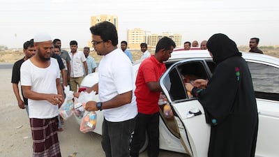 Mudassar Munaff and other volunteers distribute food packets to more than 300 labourers at a labour camp in Al Humaideyah, Ajman. Jeffrey E Biteng / The National