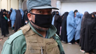 A security force member stands guard as women line up to receive rations distributed by the World Food Programme in Herat, Afghanistan, 31 March. Jalil Rezayee / EPA