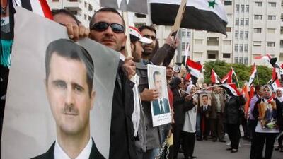 Syrian regime supporters hold portraits of Syrian President Bashar Al Assad and shout slogans against the Arab League, as they gather outside the Syrian foreign ministry in Damascus on Monday.