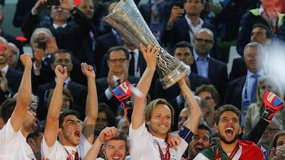 Sevilla captain Ivan Rakitic, centre, lifts the Europa League trophy as his teammates celebrate after beating Benfica on Wednesday night. Armando Babani / EPA / May 14, 2014