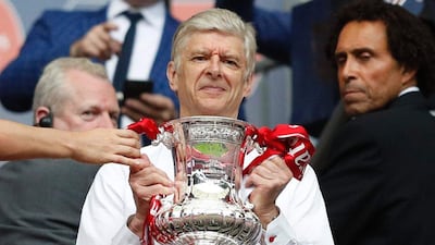 Arsenal's French manager Arsene Wenger smiles as he holds the FA Cup trophy. Adrian Dennis / AFP