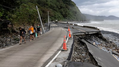 People walk near a wrecked part of the Baler-Casiguran road a day after Typhoon Fung-wong made landfall in Dipaculao, Aurora, Philippines. Reuters