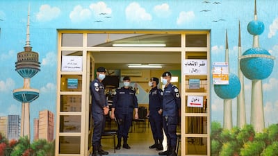 Kuwaiti police officers stand at the entrance of a polling station in Kuwait City. EPA