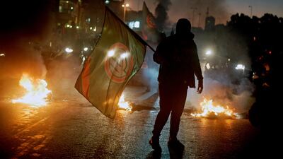 A supporter of Lebanese Parliament Speaker Nabih Berri and Amal movement carries the party's flag near burning tires during a protest in Beirut. EPA