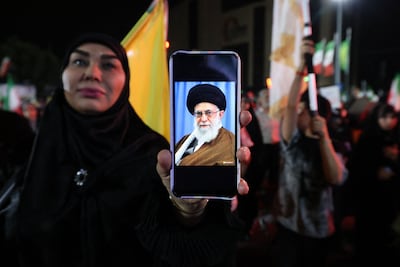 A woman in Tehran displays a picture of late Iranian Supreme Leader Ali Khamenei during a pro-government demonstration after Isreali strikes on Beirut's southern suburbs. AFP
