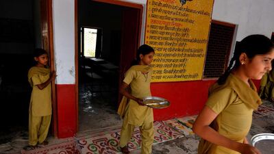 Indian schoolgirls bring their plates to be cleaned after eating lunch organised by the non-profit Akshaya Patra Foundation, at the Chaumuha Primary School on the outskirts of Vrindavan.