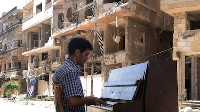 Ayham al-Ahmed, a resident of Damascus' Yarmuk Palestinian refugee camp, plays the piano in the middle of the street near destroyed buildings in southern Damascus, Syria. Rami Al Sayed / AFP