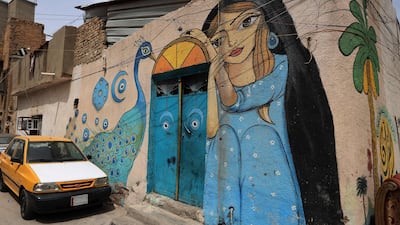 A girl and a peacock are depicted in a painting on the wall of a traditional house in street art in Baghdad's al-Anbari neighbourhood on April 10, 2023. - The Al-farasha group, an Iraqi group of artists have been painting murals inspired by traditional folklore in the narrow alleys of old Baghdadi neighbourhoods. (Photo by AHMAD AL-RUBAYE / AFP)