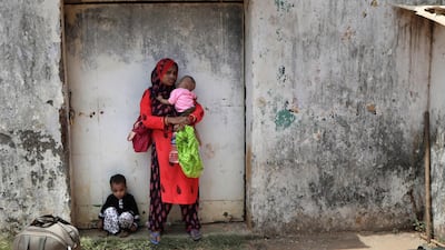 A migrant family waits to board a bus for their journey by train to their home states in Mumbai, India, May 25. On May 4, India eased lockdown rules and allowed migrant workers to travel back to their homes, a decision that has resulted in millions of people being on the move for the last two weeks. Rajanish Kakade/ AP