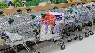 A shopping cart filled with toilet paper, kitchen paper and other products stands inside a supermarket in Sydney, Australia. Bloomberg
