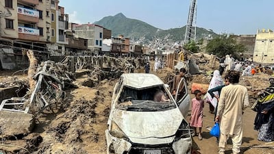 People walk through mud and debris in Mingora, the main city in Pakistan's Swat Valley, on Saturday after a flash flood. AFP