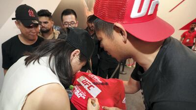 Fans with fighter Zhang Wei Li as she signs a shirt at the UFC fan zone. Chris Whiteoak / The National