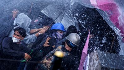 Protesters are sprayed by police water cannon at a demonstration against a revision to Indonesia's armed forces law, in front of the House of Representatives building in Jakarta. AFP