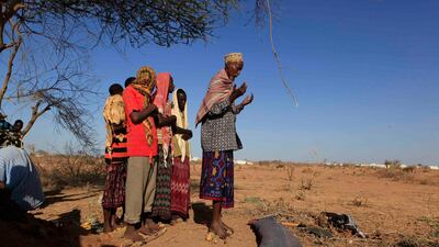 July 12, 2011: Men pray over the mat-wrapped body of 3-year-old Nasro Ahmed Gure, whose parents say died of illnesses related to malnutrition, as they prepare her for burial in an area where newly-arrived Somali refugees have settled on the outskirts of D???