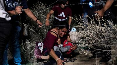 Families of migrants go under a barbed-wire fence while being escorted by a local church group to the location where they turn themselves in to the US Border Patrol in the hope of securing asylum, after crossing the Rio Grande river into the US from Mexico, in Roma, Texas. Reuters