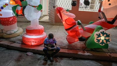 A boy looks at his phone in front of festive inflatables, as residents celebrate Christmas in Cuba's capital Havana. AFP