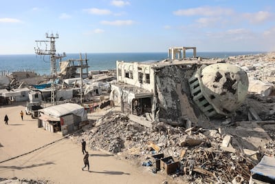 Displaced Palestinians walk past destroyed buildings and makeshift shelters near Al Shati refugee camp, west of Gaza city. AFP