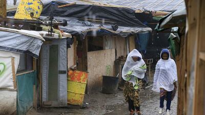 Migrants walk in the mud in the southern part of a camp for migrants called the Jungle, on a rainy winter day in Calais, northern France. Pascal Rossignol / Reuters