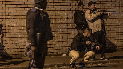 As a South African court began hearing a challenge by former president Jacob Zuma against his 15-month prison sentence, protests broke out in the streets. Here, a South Africa Police Service (Saps) officer looks on as a group of armed private security officers aims rifles at demonstrators in Jeppestown, Johannesburg..