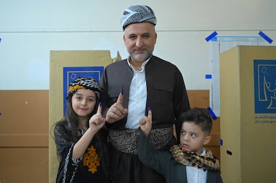 A Kurdish man in traditional dress shows his ink-marked finger after voting in Erbil. EPA