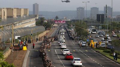 Prison warderns and members of the public watch as the procession carrying the coffin of former President Nelson Mandela makes its way past Pretoria Central Prison. Mike Hutchings / Reuters