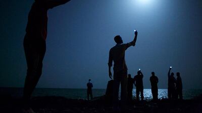 World Press Photo of the Year 2013: African migrants on the shore of Djibouti city at night, raising their phones in an attempt to capture an inexpensive signal from neighboring Somalia in Djibouti City, Djibouti. John Stanmeyer, VII for National Geographic / AP Photo