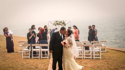The Sydney Harbour Bridge is enveloped in haze caused by nearby bushfires as a couple kisses after walking down a makeshift aisle during a wedding on the foreshore of the Sydney Harbour. AFP