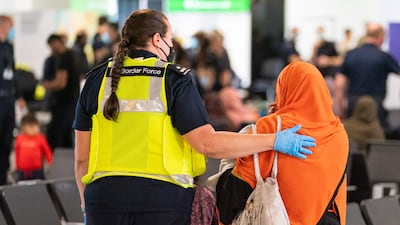 A member of Border Force staff assists an Afghan refugee on her arrival on an evacuation flight from Afghanistan, at Heathrow Airport in London. AFP