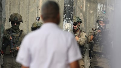 A man walks near Israeli soldiers during an army operation in the West Bank city of Nablus, on Wednesday. EPA