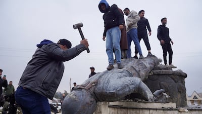 Civilians smash a statue of a Syrian Democratic Forces fighter in the city of Tabqa after the Syrian army took control on Sunday. Reuters
