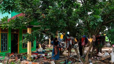 A woman retrieves clothing from a damaged building in Rajabasa. AFP