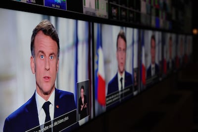French President Emmanuel Macron is seen on screens as he delivers his televised New Year's address to the nation from the Elysee Palace, in Paris on December 31, 2024. AFP
