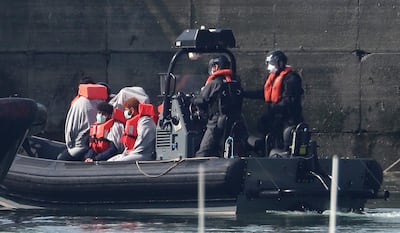 Border Force officers with men thought to be migrants, wearing face masks as they come to shore in Dover, south England, after what has been described as a small boat incident in The Channel early May 7. Gareth Fuller / AP