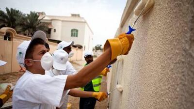 Pupils from Al Manhal Private School in Abu Dhabi paint over graffiti near their school on Wednesday as part of the Asematy community-improvement programme.