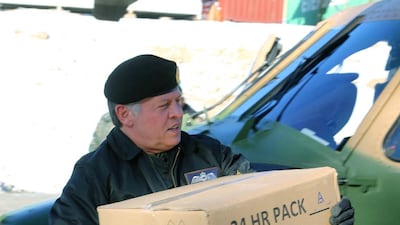 King Abdullah carryies a box containing ready meals on his visit to the Northern Command in Ajloun, part of national effort to deliver goods to citizens caught in the snowstorms in December 2013. AFP