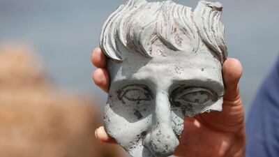 An Israel Antiquities Authority (IAA) employee holds a part of a statue that according to the IAA, was recovered from a merchant ship dated 1600 years in the ancient harbour in the Caesarea National Park. Baz Ratner / Reuters