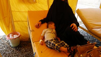 A Yemeni woman sits near her cholera-infected child as he receives treatment inside a makeshift tent at a hospital in Sanaa on July 22, 2017. Yahya Arhab / EPA